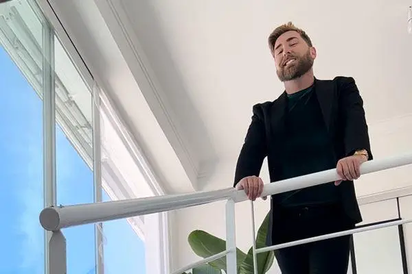 Daniel Bertram leaning on the stair railing in his new home
