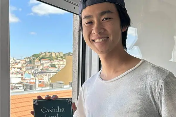 Kevin Chung at a window over Lisbon, holding a Casinha Linda Família Chung sign